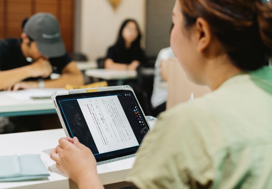Students in a Japanese classroom using a tablet for digital learning.